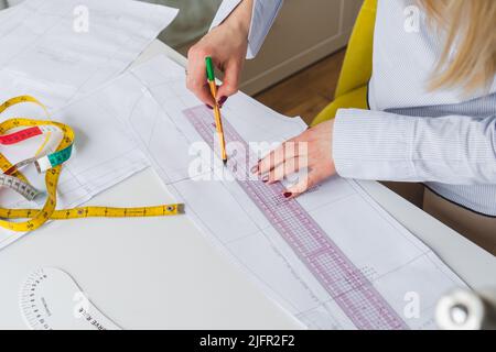 Female designer drawing paper patterns. Exclusive clothes making concept. Workplace of seamstress Stock Photo