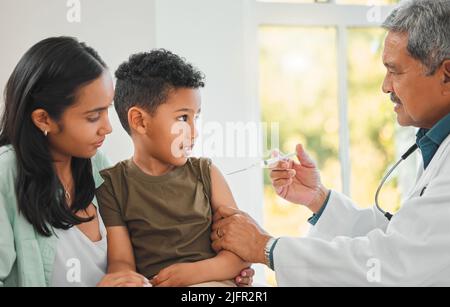 Youll have lifelong protection. Shot of a mature male doctor giving a little boy an injection at a hospital. Stock Photo