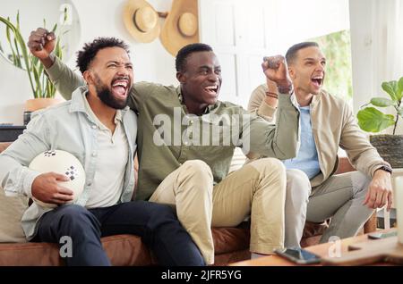 We never miss a game. Shot of three male friends watching something together while sitting on a couch. Stock Photo