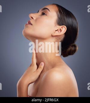 I can feel myself becoming.... Studio shot of a beautiful young woman posing against a grey background. Stock Photo