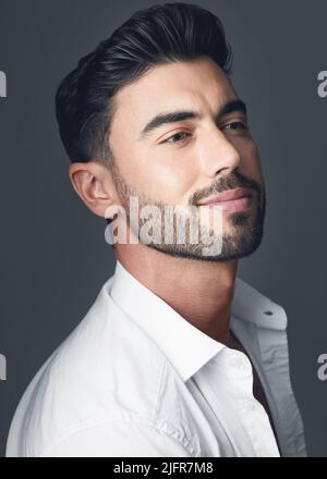Nothing says business like a crisp white collared shirt. Studio shot of a handsome young man posing against a grey studio background. Stock Photo