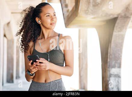 Shot of beautiful female runner standing outdoors holding water