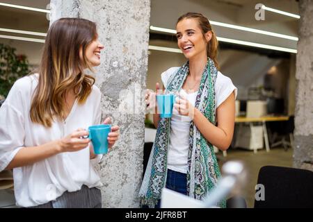 Office coffee break with two business female colleagues having fun chatting over cups of coffee Stock Photo