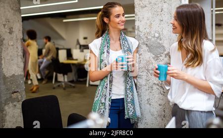 Office coffee break with two business female colleagues having fun chatting over cups of coffee Stock Photo
