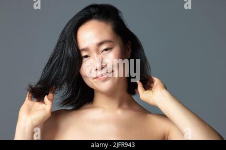 Finding the right product makes a big difference. Studio shot of a beautiful young woman posing against a grey background. Stock Photo
