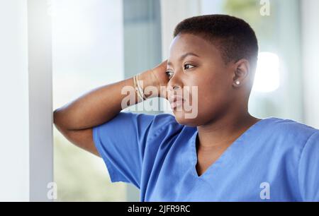 Every nurse was drawn to nursing. Shot of a female nurse looking stressed while standing in a hospital. Stock Photo