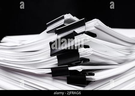 A stack of office papers, some of which are fastened with black binders Stock Photo