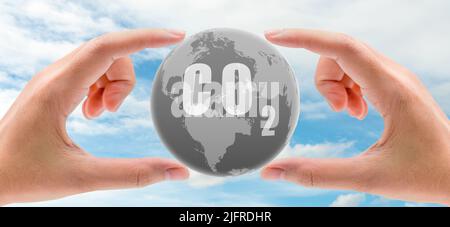 CO2 capture concept. Human hand holding CO2 in globe map on blue sky. Carbon capture and storage technology concept. Greenhouse gas. Carbon dioxide Stock Photo