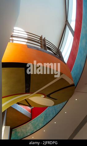 Spiral staircases with an iron railing that are painted in many pastel shades. The beautiful staircases colored and painted in different geometric sha Stock Photo