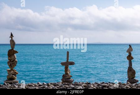 Three beautiful pile of rocks placed in perfect balance. The art of meditation and balancing stones on the beach. Stock Photo