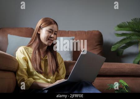 Young asian woman freelancer working on laptop in living room Stock Photo