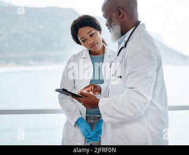 Dedicated to saving lives at all costs. Shot of two doctors using a digital tablet together in a medical office. Stock Photo