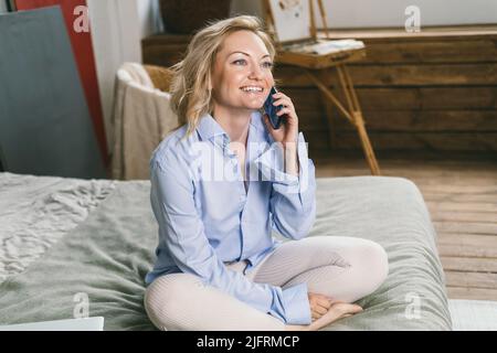 A girl with blue eyes uses a smartphone. Modern wireless communications Stock Photo