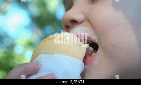 Odessa, Ukraine, Eastern Europe. 4th July, 2022. Cute little girl eats ice cream outside. Close-up portrait of blonde girl sitting on park bench and eating icecream. (Credit Image: © Andrey Nekrasov/ZUMA Press Wire) Stock Photo