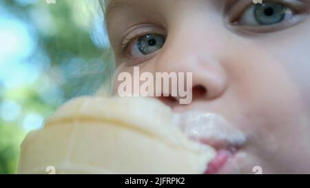 Odessa, Ukraine, Eastern Europe. 4th July, 2022. Cute little girl eats ice cream outside. Close-up portrait of blonde girl sitting on park bench and eating icecream. (Credit Image: © Andrey Nekrasov/ZUMA Press Wire) Stock Photo