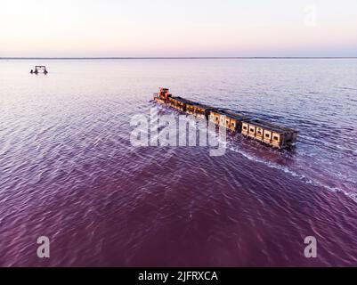 Old train rides on the railway laid in the water through the salt lake. train travels from water. Mined salt in Lake Burlin. Altai. Russia. Bursolith. Stock Photo