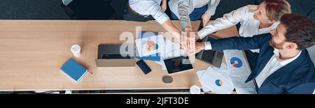 Diverse business people group put hands together while standing near the table in office Stock Photo