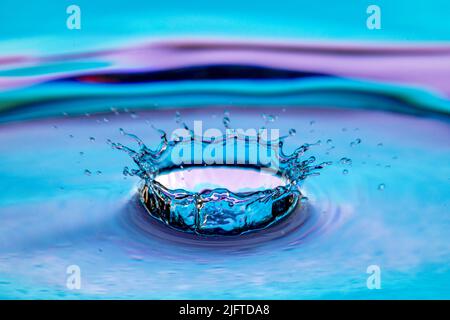 Water splash isolated on colorful background. Stock Photo