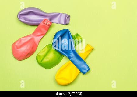 Deflated colored balloons on a green background with copy space Stock Photo