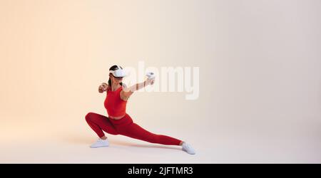 Active young woman working out in virtual reality. Sporty young woman doing fitness exercises using a pair of gaming controllers. Athletic young woman Stock Photo