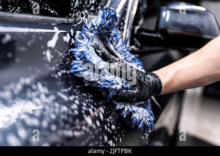 car wash employee thoroughly washes a modern ca Stock Photo
