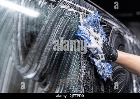 car wash employee thoroughly washes a modern ca Stock Photo