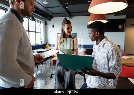 Multiracial colleagues discussing business strategy over file in creative office Stock Photo