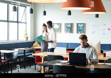 Caucasian businesswoman and african american businessman discussing over file in office Stock Photo