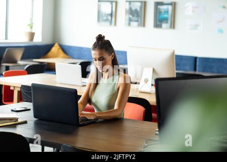 Caucasian young businesswoman working on laptop at desk in creative office Stock Photo