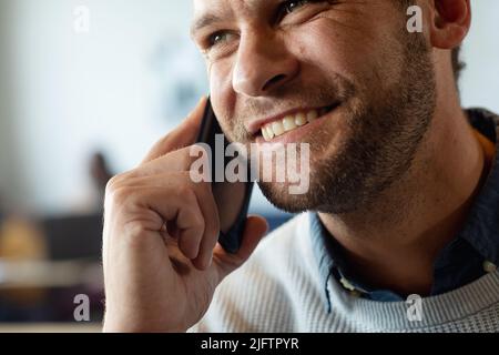 Smiling caucasian mid adult businessman talking on smart phone in office Stock Photo