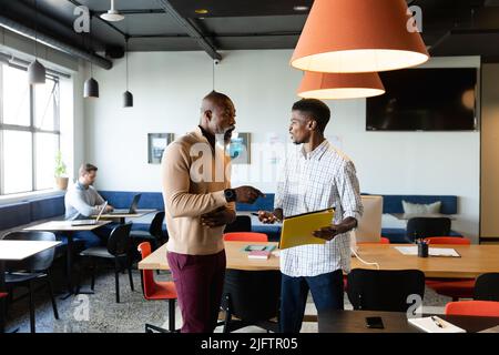African american businessmen discussing over file while standing in office Stock Photo