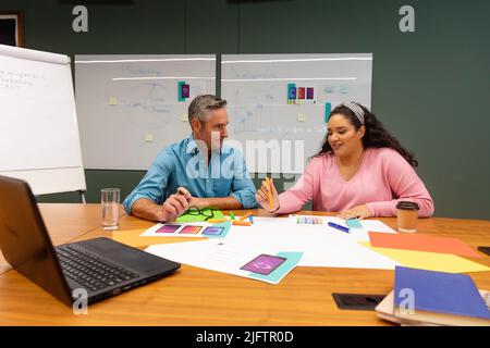 Multiracial businessman and businesswoman discussing strategy over documents in creative office Stock Photo