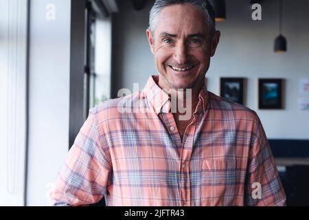 Portrait of smiling mature caucasian businessman in creative office Stock Photo
