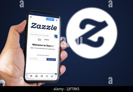 San Francisco, USA, June 2022: hand holding a phone with Zazzle homepage on the screen. Zazzle logo blurred on a blue background. Zazzle is an America Stock Photo