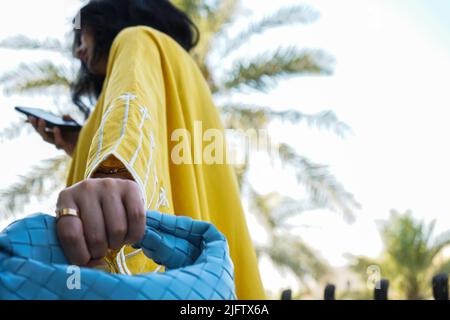 Woman wearing Yellow Abaya, Saudi Abaya and holding a bag. Stock Photo