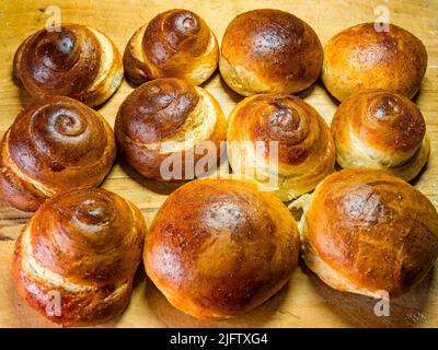 Freshly baked sweet buns and rolls buns on a wooden background - selective focus Stock Photo