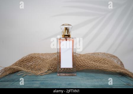 Orange Perfume bottle and cap for branding isolated on white background with green table and burlap, Red Perfume bottle mockup. Stock Photo