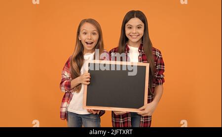 happy teen girls hold blackboard. children advertising. back to school. kids presenting information Stock Photo