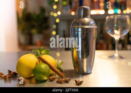 Professional bartender cocktail shaker, bar counter with lemons, limes and species with copy space for text. Stock Photo