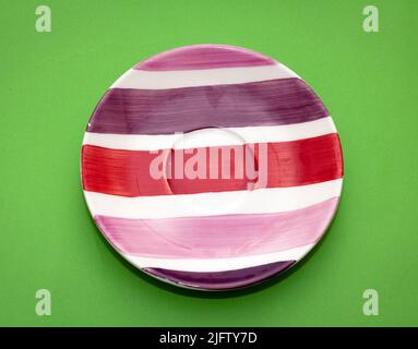 Colorful stripes empty ceramic plate isolated on green background Stock Photo