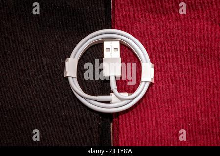 Folded connection data USB to lightning cable on textile background Stock Photo