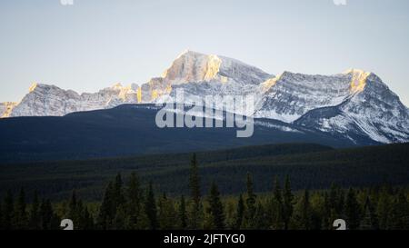 Massive rocky mountain catching the first sun rays on a cold winter morning, wide, Banff NP, Canada Stock Photo