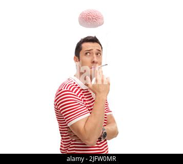 Pensive guy smoking a cigarette and thinking with brain over his head isolated on white background Stock Photo