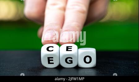 Hand turns dice and changes the expression "EGO" to "CEO". Stock Photo