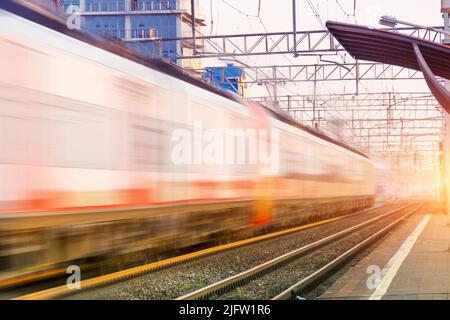 Railroad in motion at sunset. Railway station with motion blur effect against colorful blue sky. Travel, railway tourism. Blurred railway Stock Photo