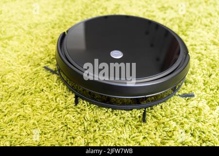 Robots vacuums cleaners on green carpet in living room for cleaning pet hair and dust. Stock Photo