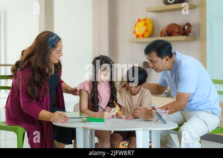 Happy Asian family with mother father daughter and son draw together in living room at home for they education when spend their family time. Stock Photo