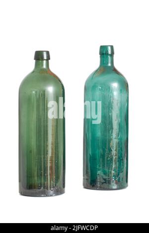 Two old empty glass bottles isolated against a white studio background with copyspace. Colourful antique glassware used as decorative art piece Stock Photo