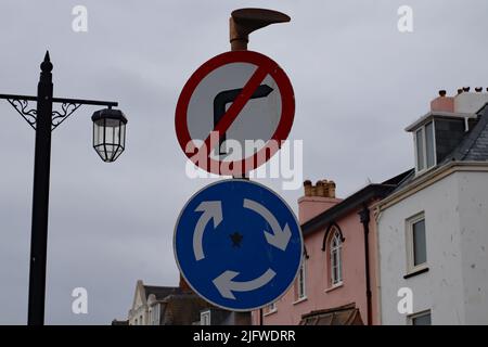 A roadsign on Sidmouth esplanade which shows a mini roundabout but with no right turn. This is because the high street is one way and it emerges at th Stock Photo