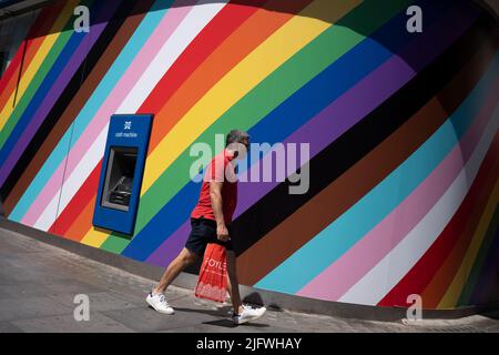 Days after the weekend's 50th anniversary LGBTQ+ Pride celebrations in the capital, the rainbow spectrum is still seen behind shoppers walking past the New Oxford Street branch of the Halifax Building Society, on 5th July 2022, in London, England. Stock Photo